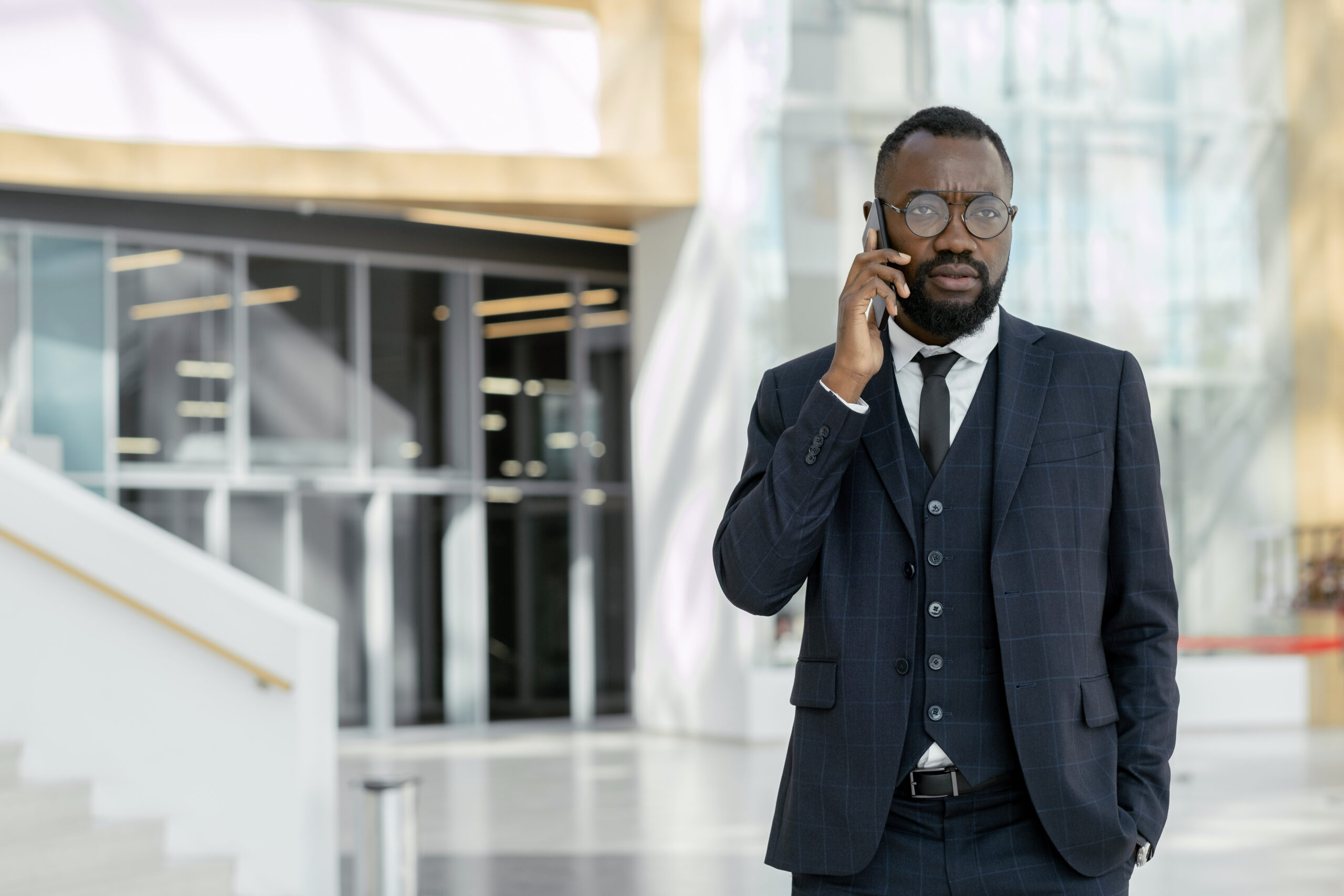 Young African businessman talking to colleague on smartphone in large mall